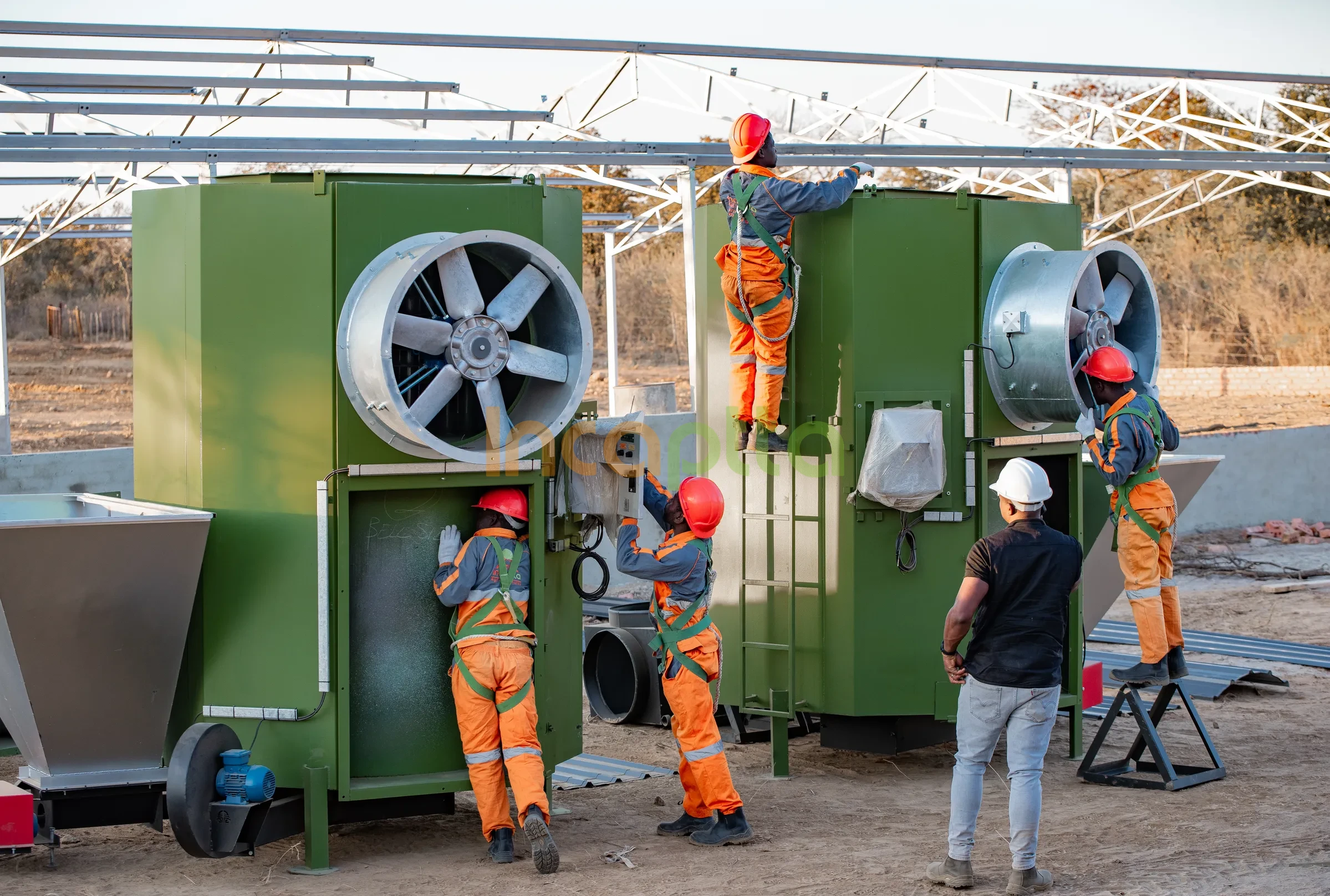 Incaptta technicians installing large climate fan units under a steel poultry house frame